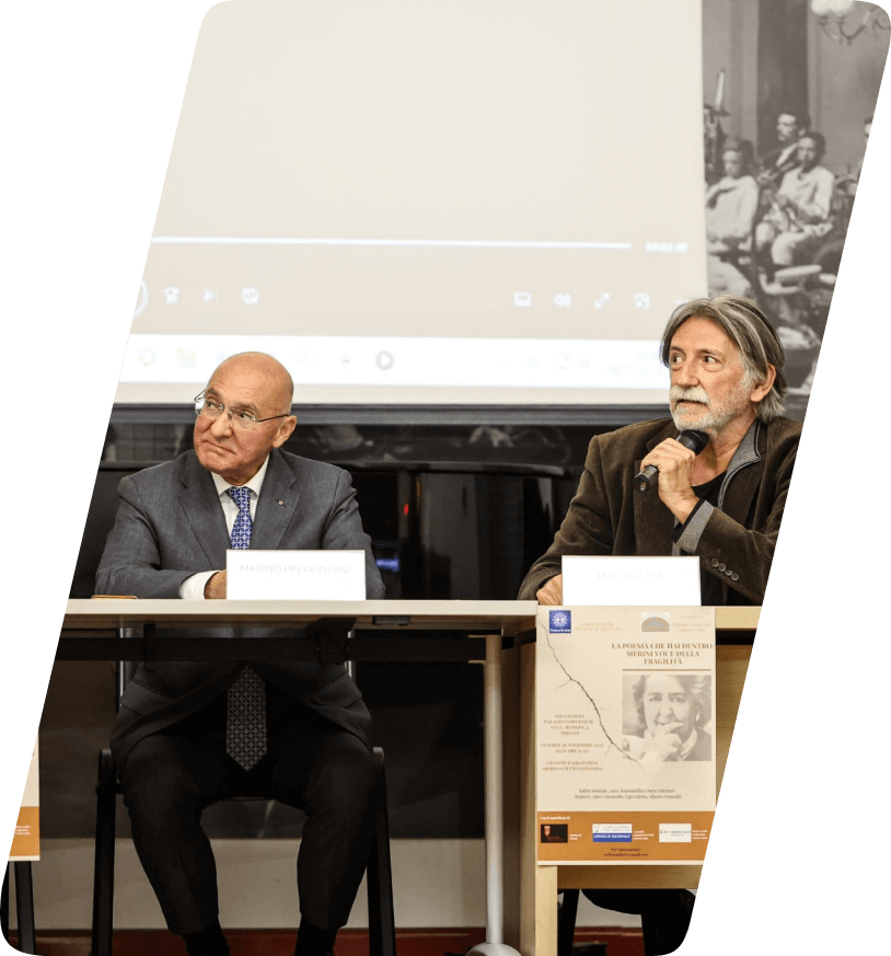 Due relatori della conferenza su Alda Merini che guardano interessati verso il terzo relatore.